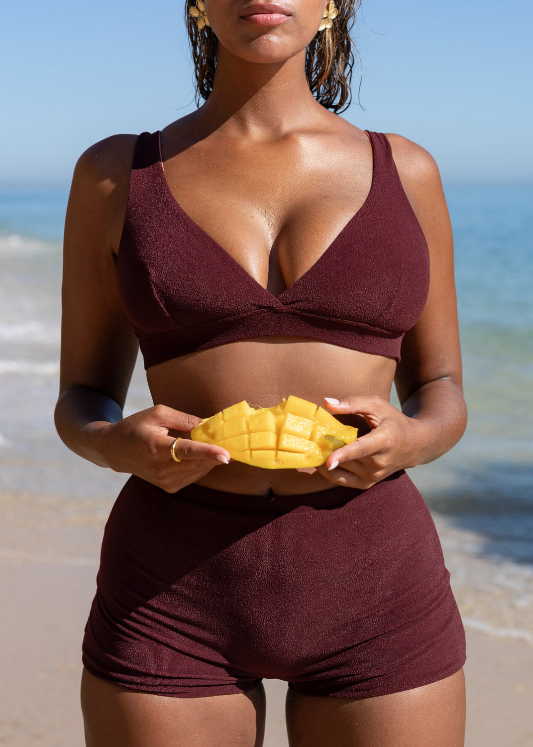 Maroon plunge top by Lilja the Label with textured fabric, worn with matching shorts and earrings.