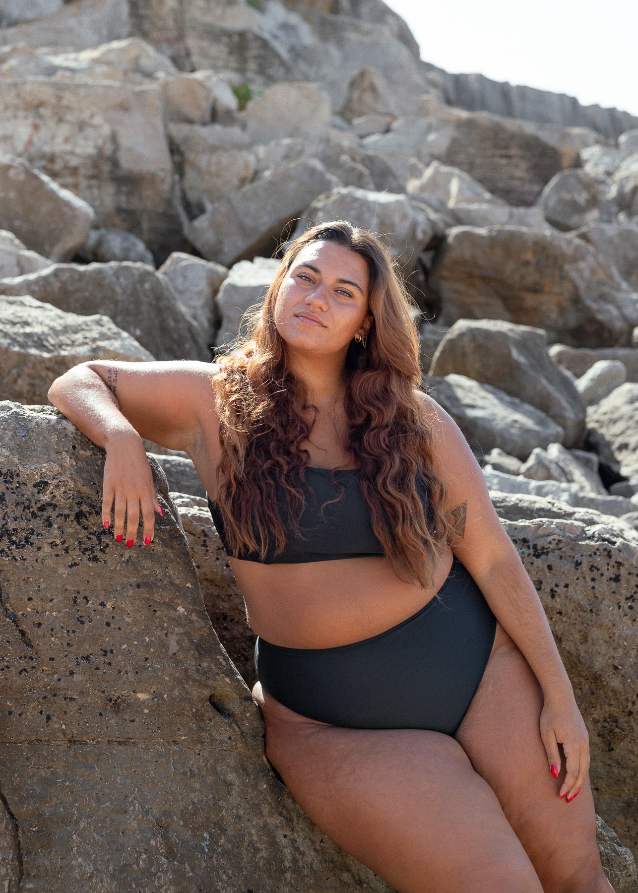 Black crop top by Lilja the Label with a woman in a bikini posing on rocks.