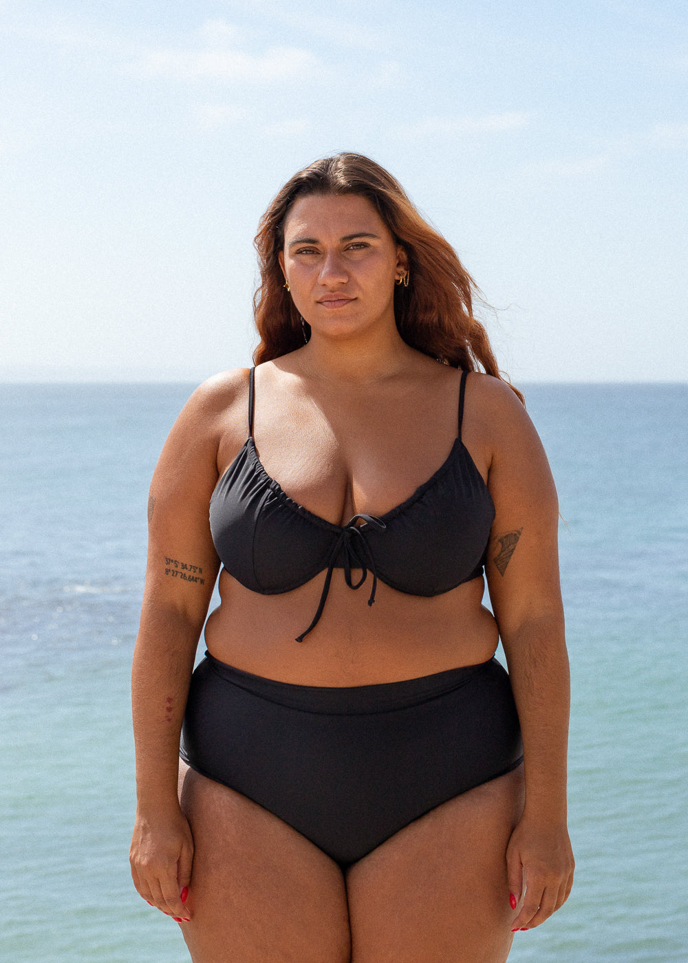 Black drawstring top by Lilja the Label with tie detail, worn with high-waisted black bikini bottoms.