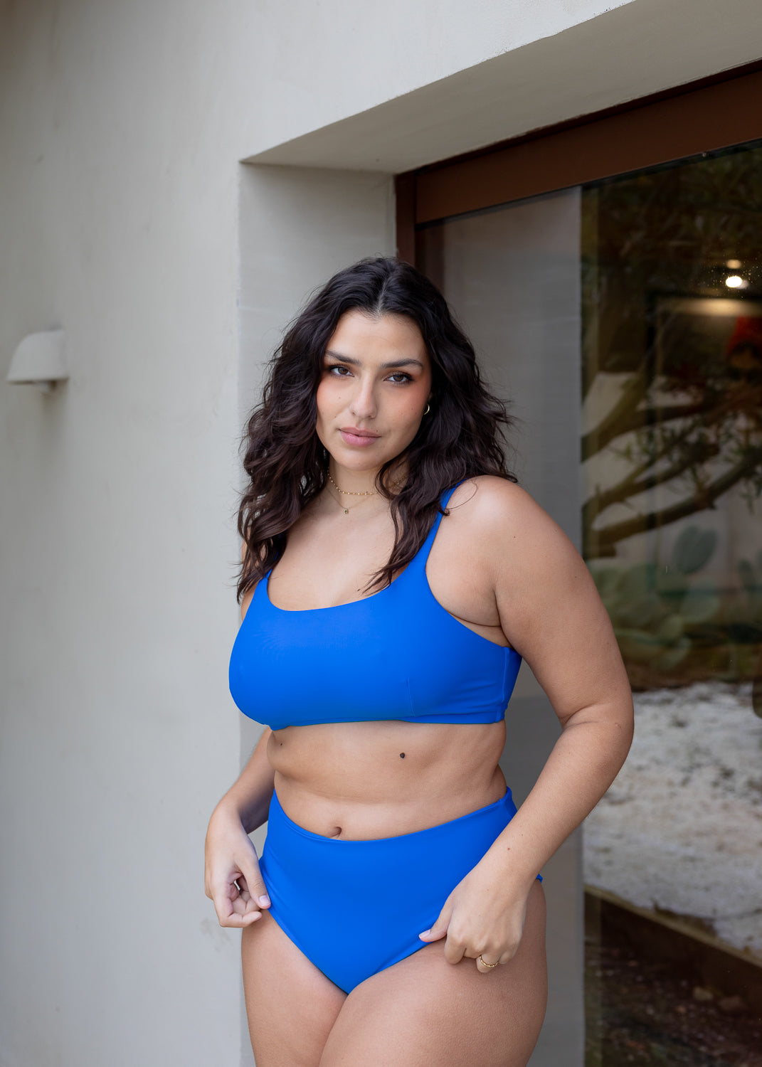 Blue crop top by Lilja the Label, worn with matching high-waisted bottoms, in front of a doorway.