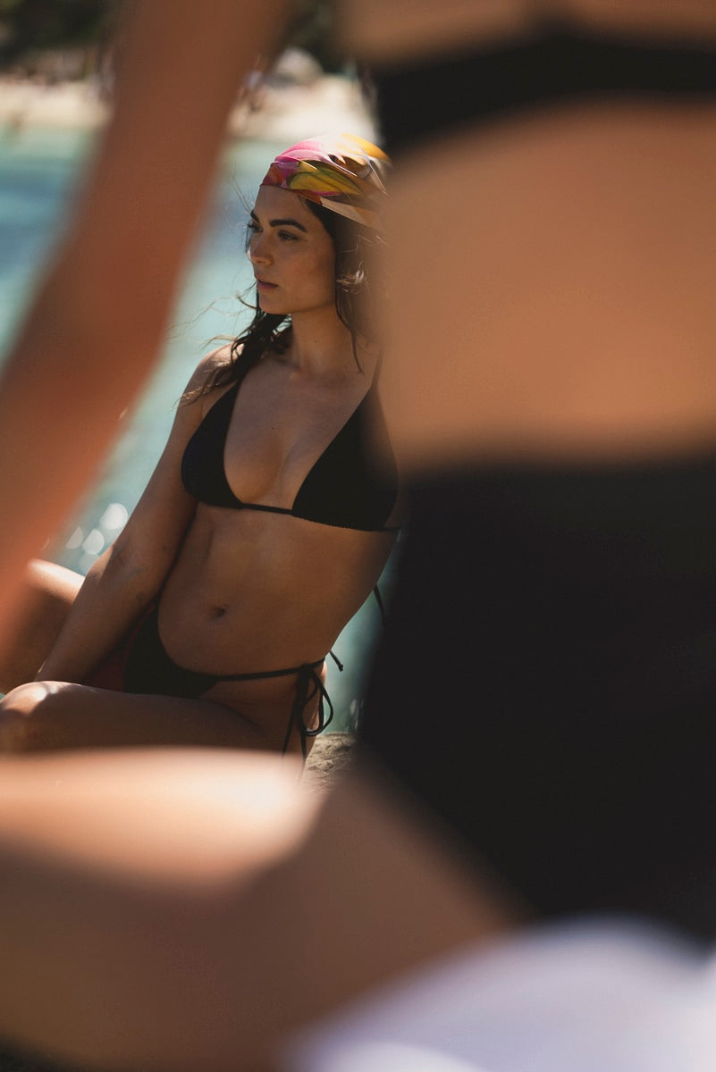 Black bottoms by Lilja the Label, seen on model with drawstring ties at hips, in beach setting.