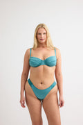 Teal gathered bottom bikini bottoms by Lagoon, featuring ruched sides and a high-cut leg style in a smooth fabric, shown on a model in full length view.